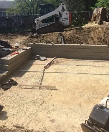 A block retaining wall with a screeded base, rails and a compactor ready