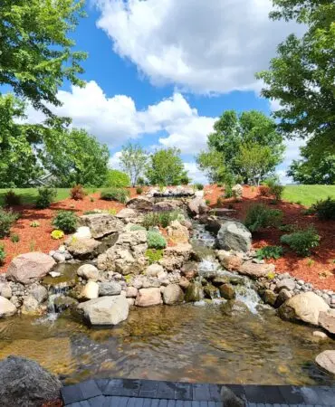 A rock waterfall and stream feature built into a landscaped yard